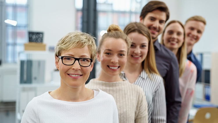 Menschen in einer Reihe hintereinander, mit Happy Gesichtern, in einem Büro.